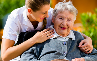 Infirmière embrassant une vieille dame en fauteuil roulant souriant