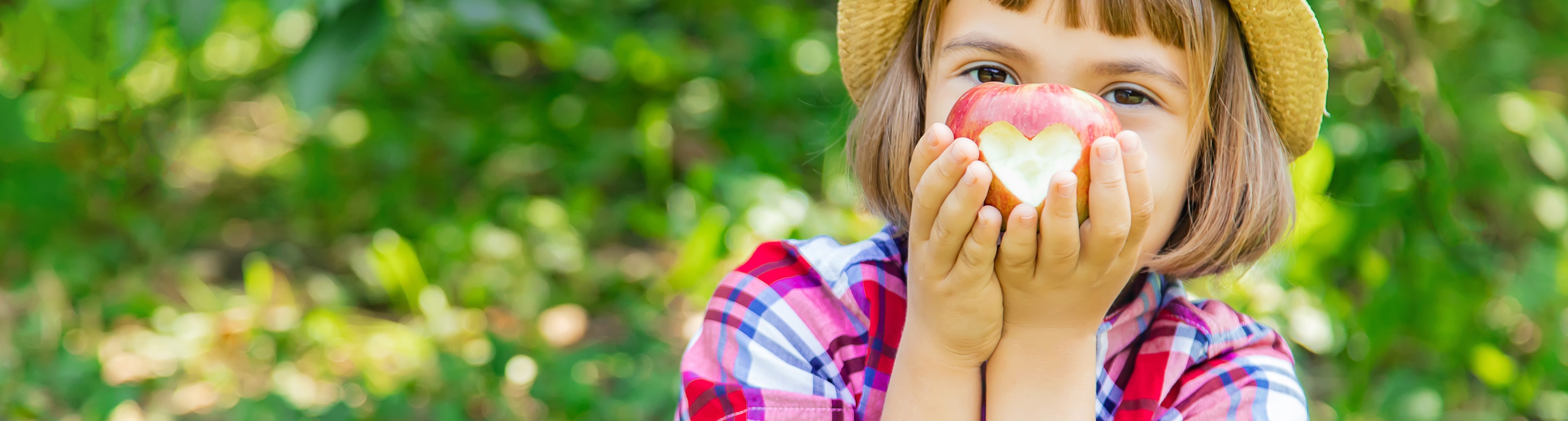 Petite fille tenant une pomme devant son visage